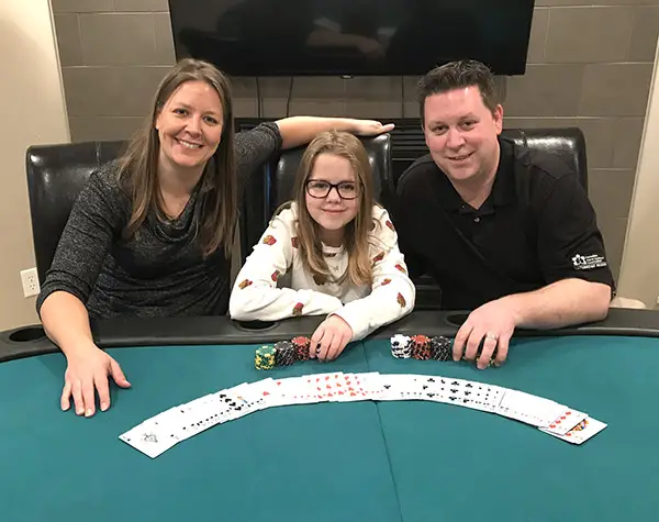 a group of people sitting at a table with cards and chips